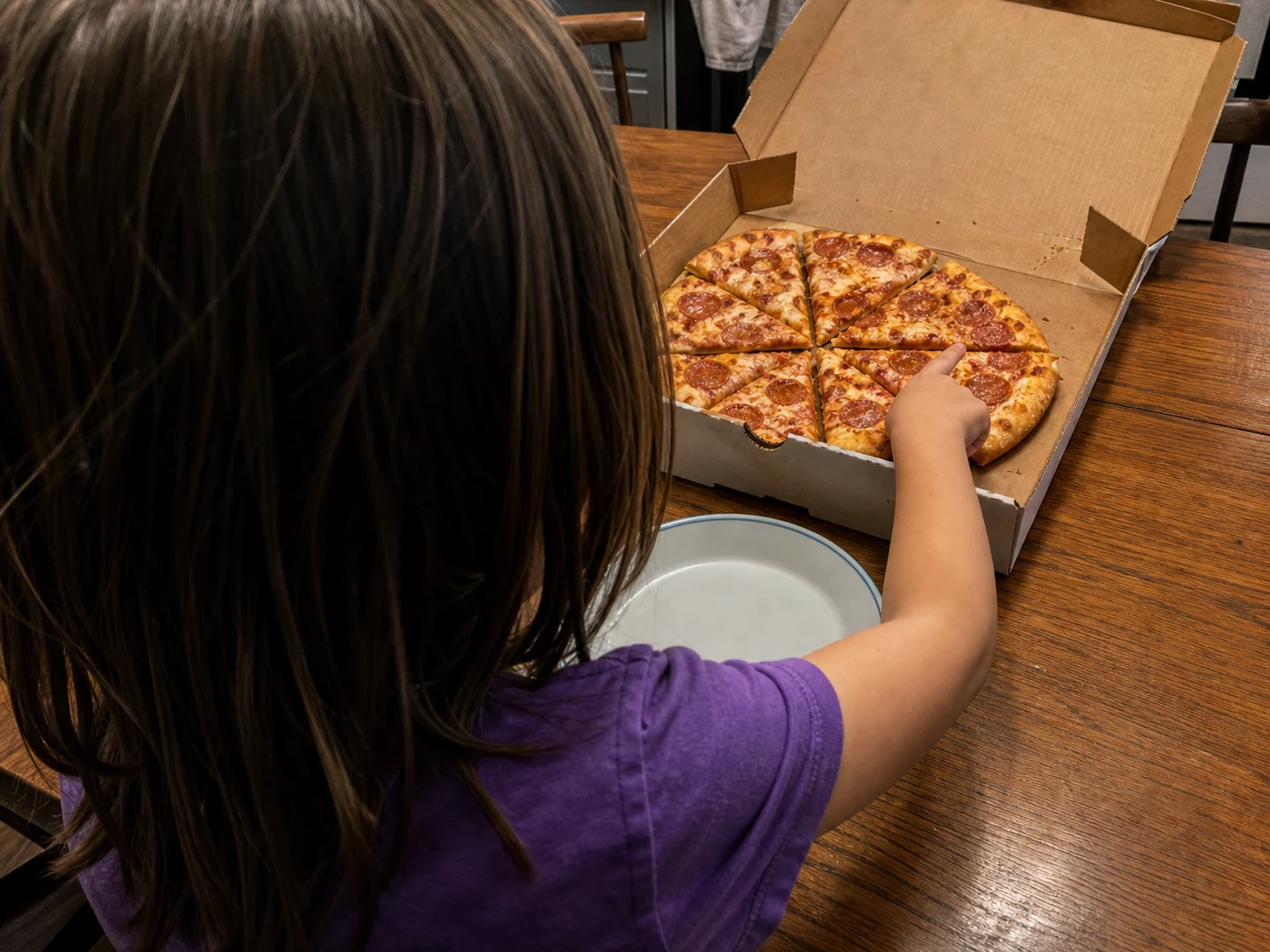 Example photo from behind of a child looking closely at pizza slices